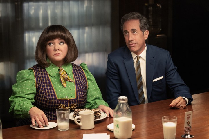 A woman and man sit next to each other at a table and stare.